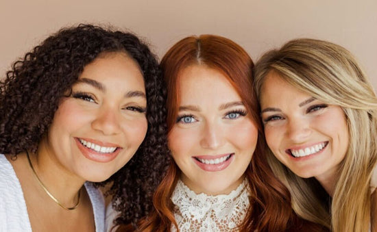 Three women smiling close together showing off their DIY eyelash extensions.